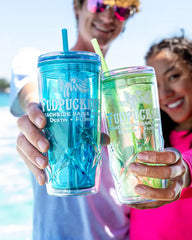 Two people holding blue and green tumblers with 'Fudpucker's' branding, outdoors.